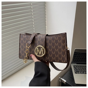 Close-up of vintage brown monogram bag with golden M metal clasp and leather strap