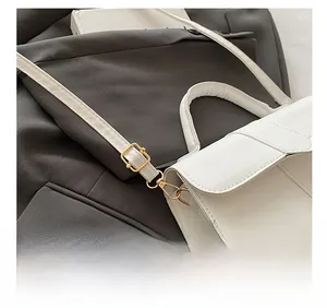 Detailed view of white PU leather bag featuring gold-toned metal buckles and adjustable strap