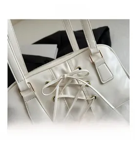 Detail of white PU leather tote with unique criss-cross lacing and golden eyelets