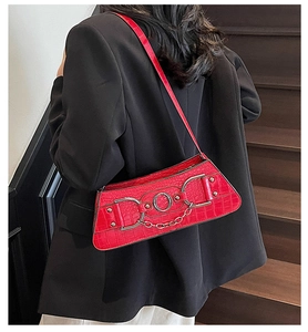 Detail of red crocodile texture underarm bag with vintage metal rings and chain