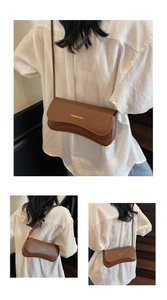 Detail of caramel brown underarm bag with asymmetric flap and golden fashion engraving