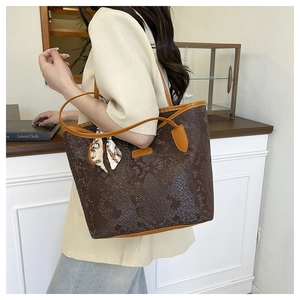 Detail of dark brown snakeskin tote bag with decorative equestrian print silk scarf