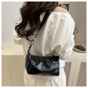 Detailed view of black glossy shoulder bag with sleek metallic zipper and patent leather finish