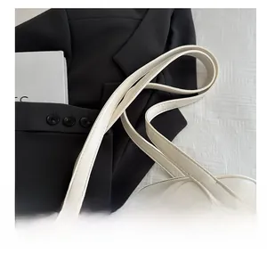 Detailed shot of cream leather bag straps with golden rings and refined stitching