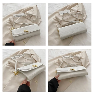 Macro detail of white crocodile texture handbag with gold buckle and slim strap