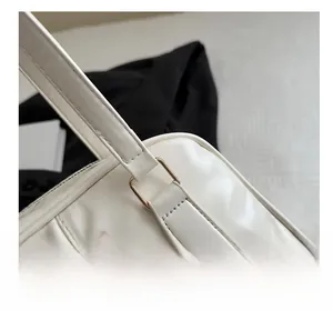 Detail of ivory leather shoulder bag with gold square buckle and stitching accents