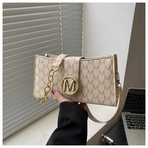 Detailed close-up of M-patterned beige leather bag with golden metallic clasp and chain