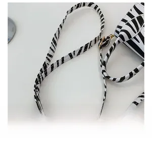 Adjustable shoulder strap detail of zebra print handbag with gold-tone hardware