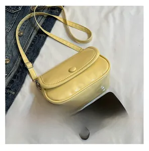 Detailed view of yellow patent leather small square crossbody bag with round buckle