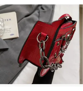 Close-up of red crocodile embossed leather texture with silver metal chain and rivets