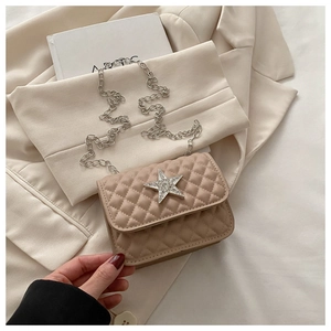 Detail of beige quilted mini bag featuring a large sparkling rhinestone star and chain