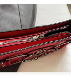 Detail view of red crocodile embossed leather bag with silver metal zipper and chain strap