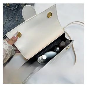 Interior view showing the capacity of this white leather crossbody bag with pearl charm