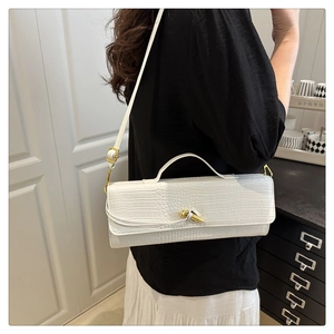 Detailed macro view of white crocodile pattern texture and golden metal knot on handbag
