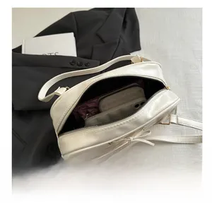Internal view of cream leather bow bag showing spacious storage for phone and essentials