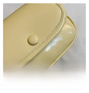 Close-up of yellow pebbled leather crossbody bag showing fine stitching and snap button