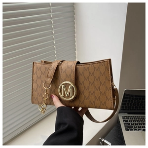 Detail of monogram M print bag with golden metal buckle and sleek leather texture