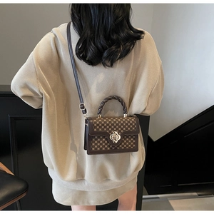 Retro brown geometric handbag with golden flower buckle shown on a stylish model