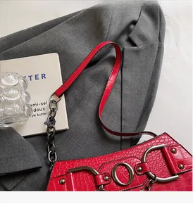 Macro detail of red crocodile embossed texture with thick metal chain on a baguette bag
