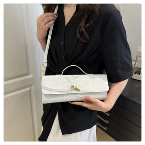 Detail of white crocodile pattern shoulder bag with a gold metal twist lock and strap