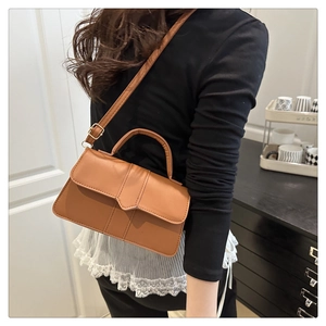 Brown faux leather baguette bag worn crossbody by a model in a minimalist home setting