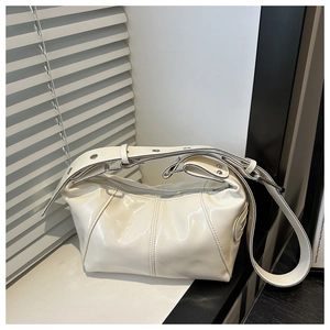 Close-up of cream glossy moon bag with decorative silver metal eyelets on the wide strap