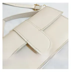 Detailed close-up of cream leather shoulder bag with gold hardware and fine stitching
