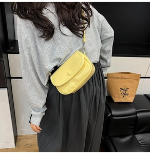 Detail of a creamy yellow crossbody bag with smooth finish and adjustable shoulder strap