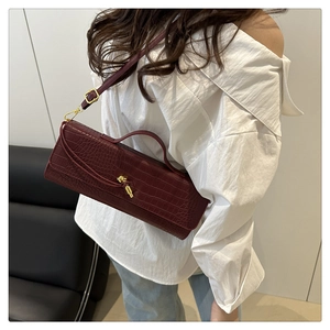 Detail of dark red crocodile pattern handbag featuring a gold twist-lock buckle