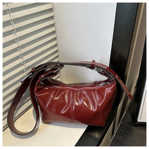 Detail of burgundy glossy leather shoulder bag with adjustable silver buckle strap