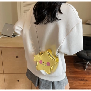 Detail der gelben sternförmigen Umhängetasche mit Cartoon-Gesicht und Kette am Modell getragen