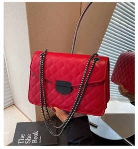 Détail du sac à bandoulière matelassé rouge avec chaîne en métal et fermoir pivotant