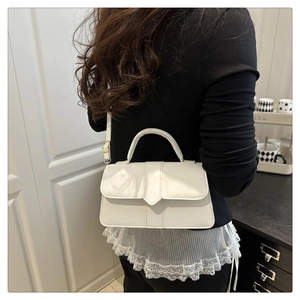 Detail of elegant ivory leather handbag with gold hardware and adjustable strap