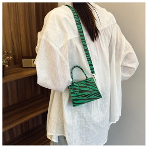 Detailed shot of a zebra print mini crossbody bag with green animal pattern and strap