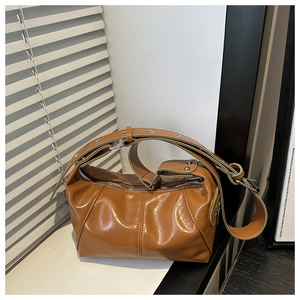 Close-up of brown patent leather shoulder bag with glossy finish and metal buckles