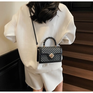 Detail of vintage square handbag featuring a golden flower clasp and woven handle