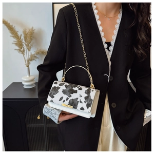 Detalle de un bolso con estampado de vaca llevado por una modelo con blazer negro