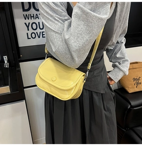 Close-up of vibrant yellow saddle bag with glossy finish and circular buckle detail