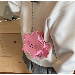 Detail of pink star-shaped crossbody bag featuring a smiling face and silver chain strap