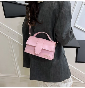 Detail of pink faux leather handbag featuring a curved flap and gold Fashion logo