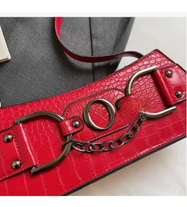 Detail of red crocodile texture belt featuring bold punk metal chain and D-ring buckles