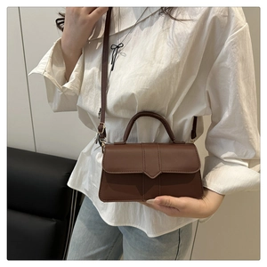 Brown matte leather crossbody bag shown on model with casual white shirt and jeans