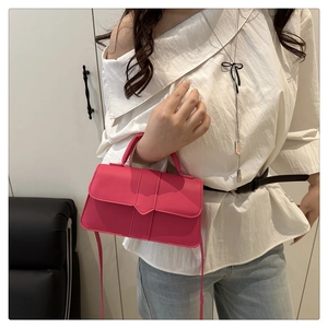 Detail of a bright magenta crossbody square bag with top handle and matching shoulder strap
