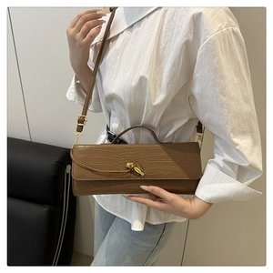 Close-up of brown crocodile texture leather bag with a gold knot metal buckle detail