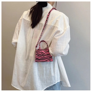 Close-up of mini zebra print crossbody bag in pink and black on model back view