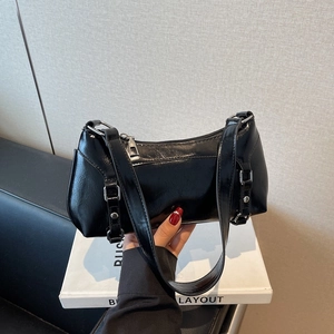 Glossy black minimalist baguette underarm bag with silver hardware held in hand