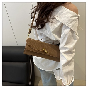 Detail of crocodile embossed leather texture and gold knot lock on the brown handbag