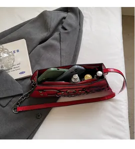 Interior view of red crocodile-pattern shoulder bag with phone and lipstick details
