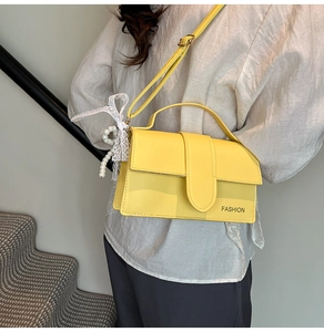 Close-up of a yellow faux leather handbag with lace bow and pearl charm detail