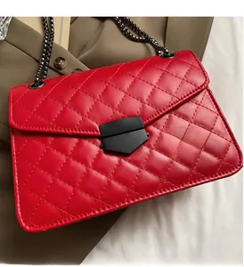 Détail du sac rouge en cuir matelassé avec fermoir noir mat et bandoulière en chaîne